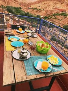 une table en bois avec des assiettes de nourriture et de jus d'orange dans l'établissement Kasbah Tinariwin, à Taziricht