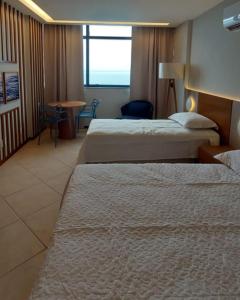a hotel room with two beds and a table at Sol Vicitoria Marina in Salvador