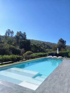 une grande piscine bleue avec des chaises et des arbres dans l'établissement Turismo Natureza Villa Rio, à Castanheira de Pêra