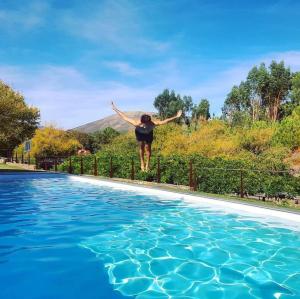 a woman jumping in the air over a swimming pool at Turismo Natureza Villa Rio in Castanheira de Pêra