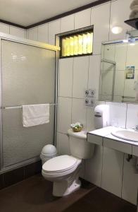 uma casa de banho com um WC, um lavatório e um espelho. em Brillasol Airport Hotel em Alajuela