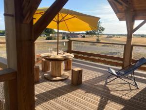 a table with an umbrella and a chair on a deck at l'Observatoire de l'Aérogrange in Biscarrosse