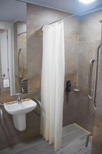 łazienka z zasłoną prysznicową i umywalką w obiekcie Íbis Styles Itaúna w mieście Itaúna