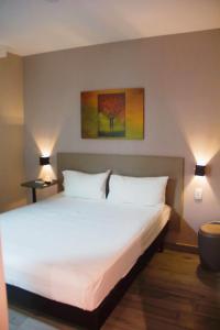 sypialnia z dużym białym łóżkiem z 2 lampami w obiekcie Íbis Styles Itaúna w mieście Itaúna