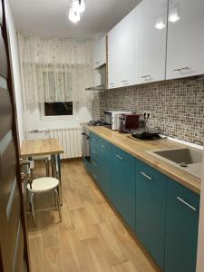 een keuken met blauwe kasten en een houten vloer bij Turquoise Studio Nerva Traian in Boekarest