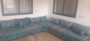 Settat Zen Ferme في Maachat: أريكة زرقاء في غرفة المعيشة مع نافذتين