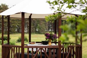 a gazebo with a table and flowers on it at Coastal Home Muini Ūši in Kolka