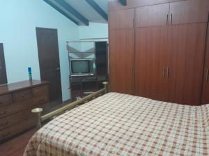 1 dormitorio con 1 cama, TV y armarios de madera en LA CASA DE SYLVANA, en Quito