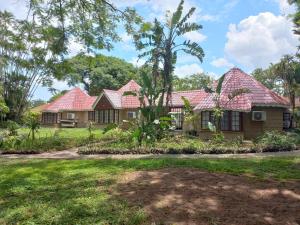 une maison avec des toits rouges dans une cour dans l'établissement Marula Gardens, à Mtubatuba