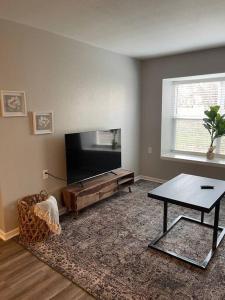 a living room with a flat screen tv and a table at The Carolyn - 2 Bedroom Apt in Quilt Town, USA in Hamilton +5 photos