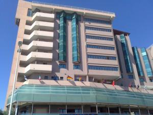 un grand bâtiment avec des drapeaux devant lui dans l'établissement Pegasus Hotel, à Sassari