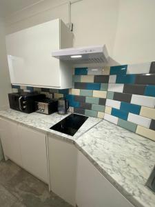 a kitchen with white cabinets and a tile wall at 1 bedroom Luxury Apartments by London City in London