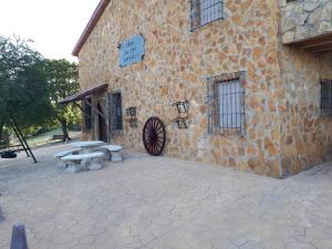 un edificio de piedra con una mesa de picnic delante de él en Casa El Tío Patricio, en Trujillos