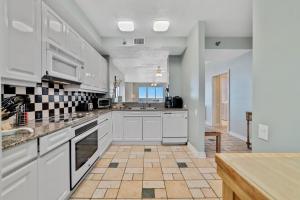 a kitchen with white cabinets and a tile floor at Beach Colony Tower 12B in Perdido Key