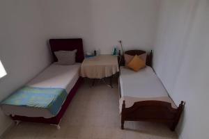 a room with two beds and a table in it at Sahline, entre Sousse et Monastir, 2 Km de la plage in Sahline