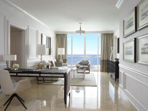a white living room with a desk and chairs at Acqualina Resort and Residences in Miami Beach