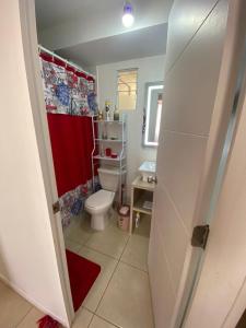 uma casa de banho com um WC e uma cortina de chuveiro vermelha. em A pasos del mar Lugar ideal para descansar em El Tabo