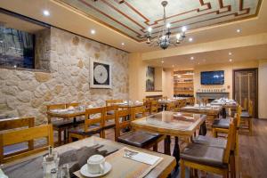 a restaurant with wooden tables and chairs and a stone wall at Hotel Kassaros in Metsovo