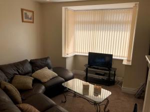 a living room with a leather couch and a tv at Angie’s hideaway in Balby