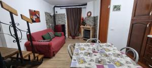 a living room with a table and a red couch at Appartamento in una valle di Luce in Pizzoferrato
