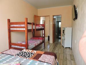 a room with two bunk beds and a kitchen at Rm Pousada Casa De Familia in São Gabriel