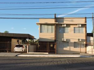 ein Gebäude mit einem Zaun und einem davor geparkt in der Unterkunft Rm Pousada Casa De Familia in São Gabriel