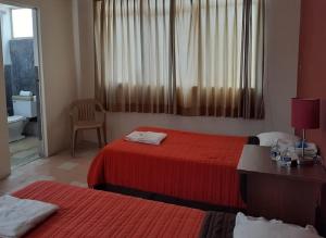 um quarto de hotel com duas camas e uma janela em HABITACIÓN AZALEA, BAÑO PRIVADO Y COCINETA. em Tepic