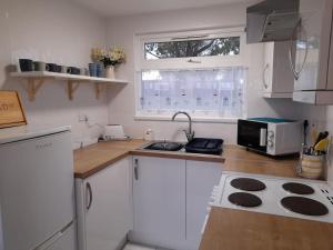 a kitchen with white cabinets and a stove top oven at 'Sunnyside' Chalet, walk to the beach & close to Norfolk broads - pet friendly! in Great Yarmouth