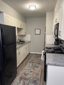 cocina con nevera negra y armarios blancos en The Irene - 2 Bedroom Apt in Quilt Town, USA, en Hamilton
