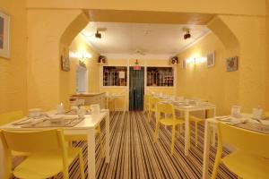 a restaurant with white tables and yellow chairs at The Rosslyn in Paignton