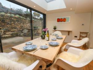 comedor con mesa de madera y sillas blancas en Woodlea Cottage, en Huddersfield