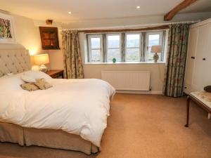 Un dormitorio con una gran cama blanca y una ventana en Woodlea Cottage, en Huddersfield
