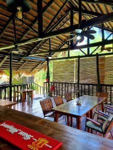 a restaurant with wooden tables and chairs and a ceiling at Binga Beach Palawan Glamping in San Miguel