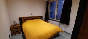 a yellow bed in a room with a window at Nez sur la croisette. in Dinant