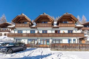 a house with a car parked in front of it in the snow at Ferienwohnung AlmLust in Hochrindl