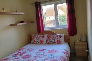 a bedroom with a bed and a window with red curtains at Lovely Cosy Apartment near Water Parks in South Cerney