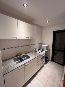 una cucina con mobili bianchi, un lavello e una stufa di Paris Aparts a Colón