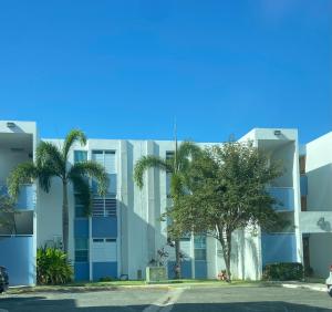un bâtiment avec des palmiers en face de celui-ci dans l'établissement cozy private apartment near sju airport, à Carolina
