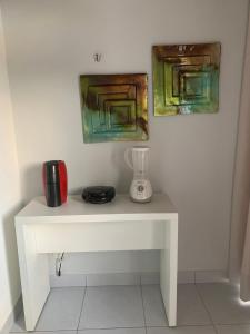 a white table with a blender and two paintings at Pipa Ubaia 219 com solarium in Pipa