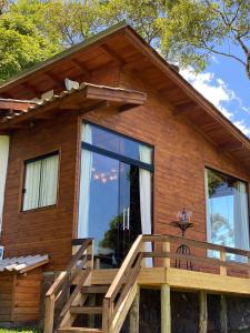a log cabin with a large window and a deck at Pousada recanto do vinho in Rio Rufino