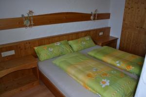 1 cama con 2 sábanas verdes y 2 almohadas en Landhaus Leutaschtal, en Leutasch