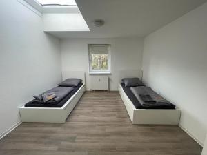 2 bedden in een witte kamer met een raam bij Zimmervermietung Am Airport in Bremen