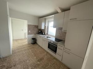 a small kitchen with white cabinets and a window at Zimmervermietung Am Airport in Bremen