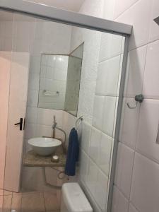 een badkamer met een wastafel, een toilet en een spiegel bij Casa conchas das Caravelas in Governador Celso Ramos