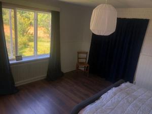 a bedroom with a bed and a window and a chair at Comfortabel Zweeds huis met sauna en houtkachel. in Öje