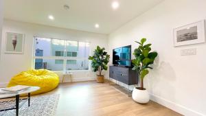 a living room with a television and a yellow ottoman at Kingsley Courtyard Apartment in Los Angeles