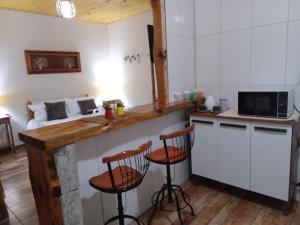 a kitchen with a counter and stools in a room at Recanto KAIRÓS in Visconde De Maua