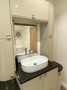A spacious & modern 3-bed home في بلاكبيرن: حمام مع حوض أبيض ومرآة