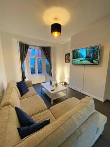 een woonkamer met een bank en een tafel bij A spacious & modern 3-bed home in Blackburn