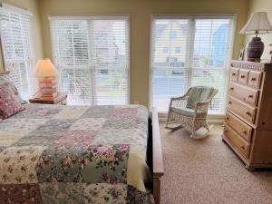 Un dormitorio con una cama, una cómoda y ventanas. en Le Tournesol, en Holden Beach